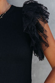 Black ribbed knit blouse with sheer polka dot tulle ruffle sleeves.