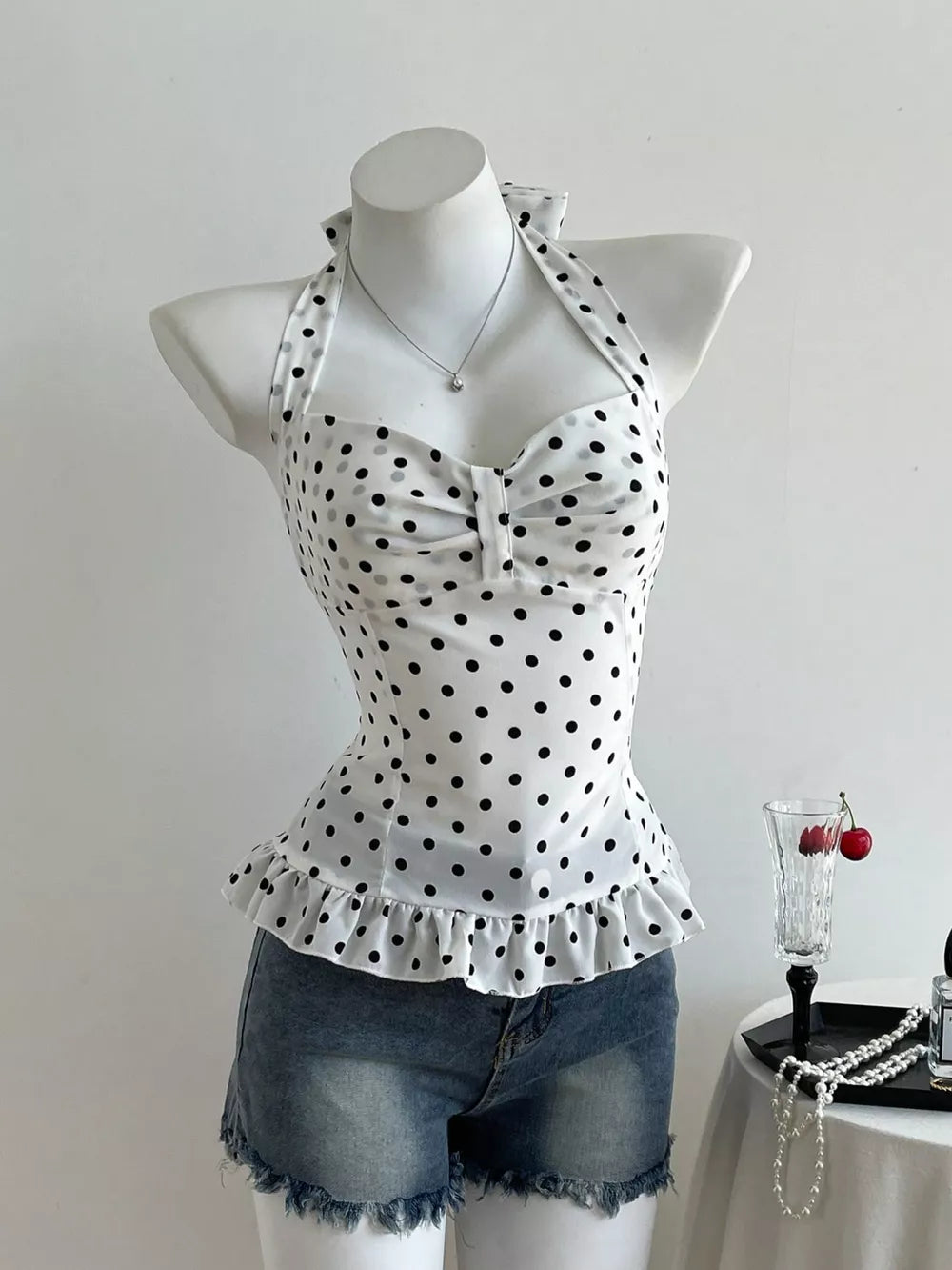 White polka dot halter cami with ruffled hem and decorative bow detail