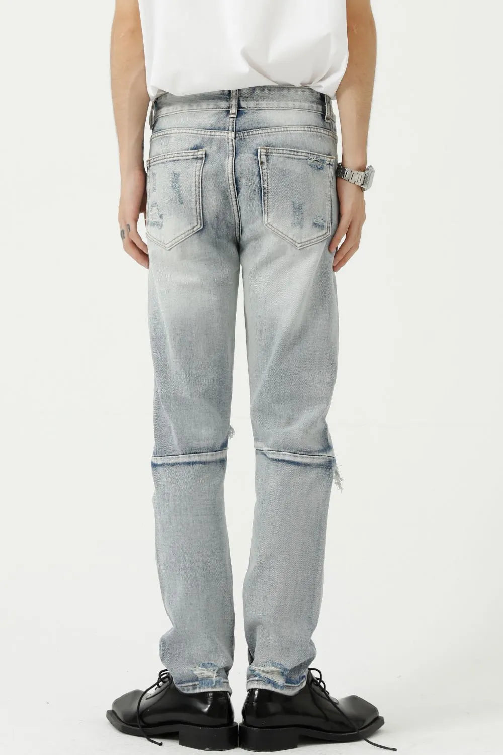 Light wash ripped knee slim fit denim jeans with distressed details and a raw hem.