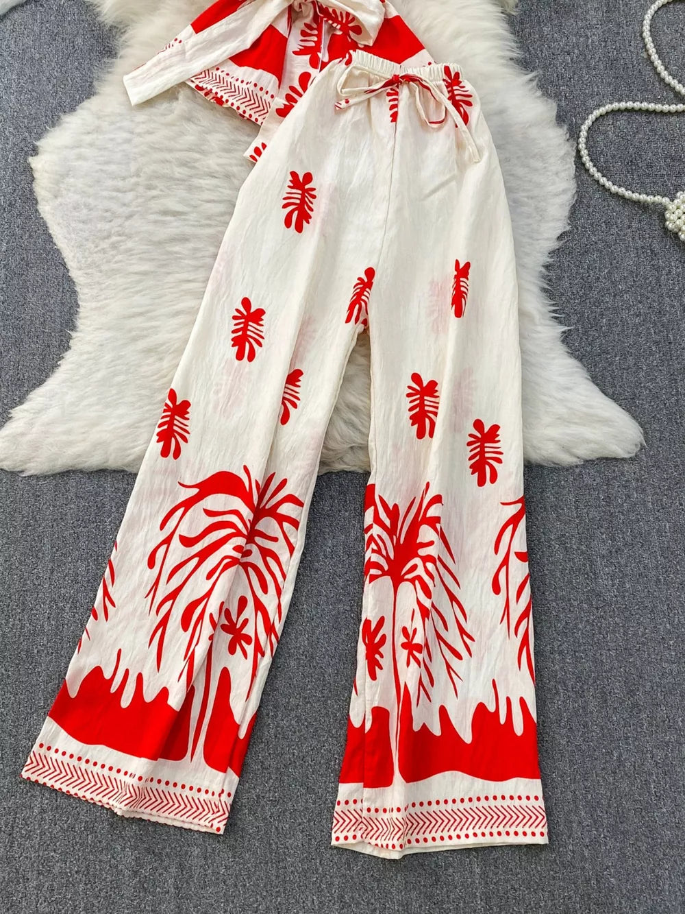 Red tropical print wide leg pants with drawstring waist and a matching belted top.