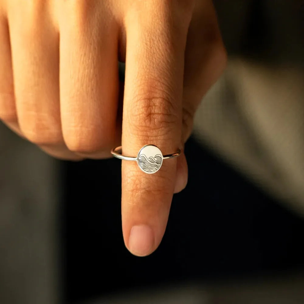Silver ring with engraved wave pattern on a round face, casual band style