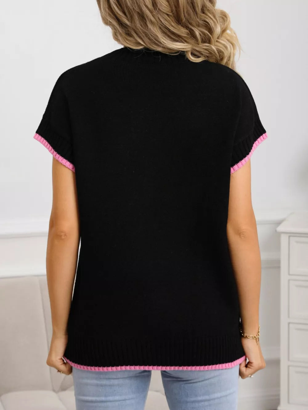 Black knit top with pink ribbed crew neck, cuffs, and hem