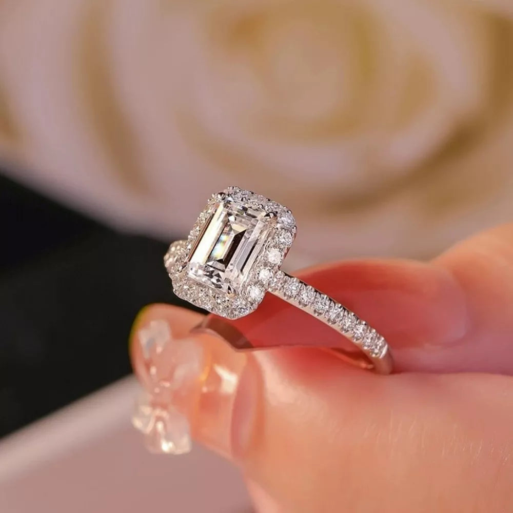 Radiant moissanite engagement ring in silver with emerald cut center stone and halo.