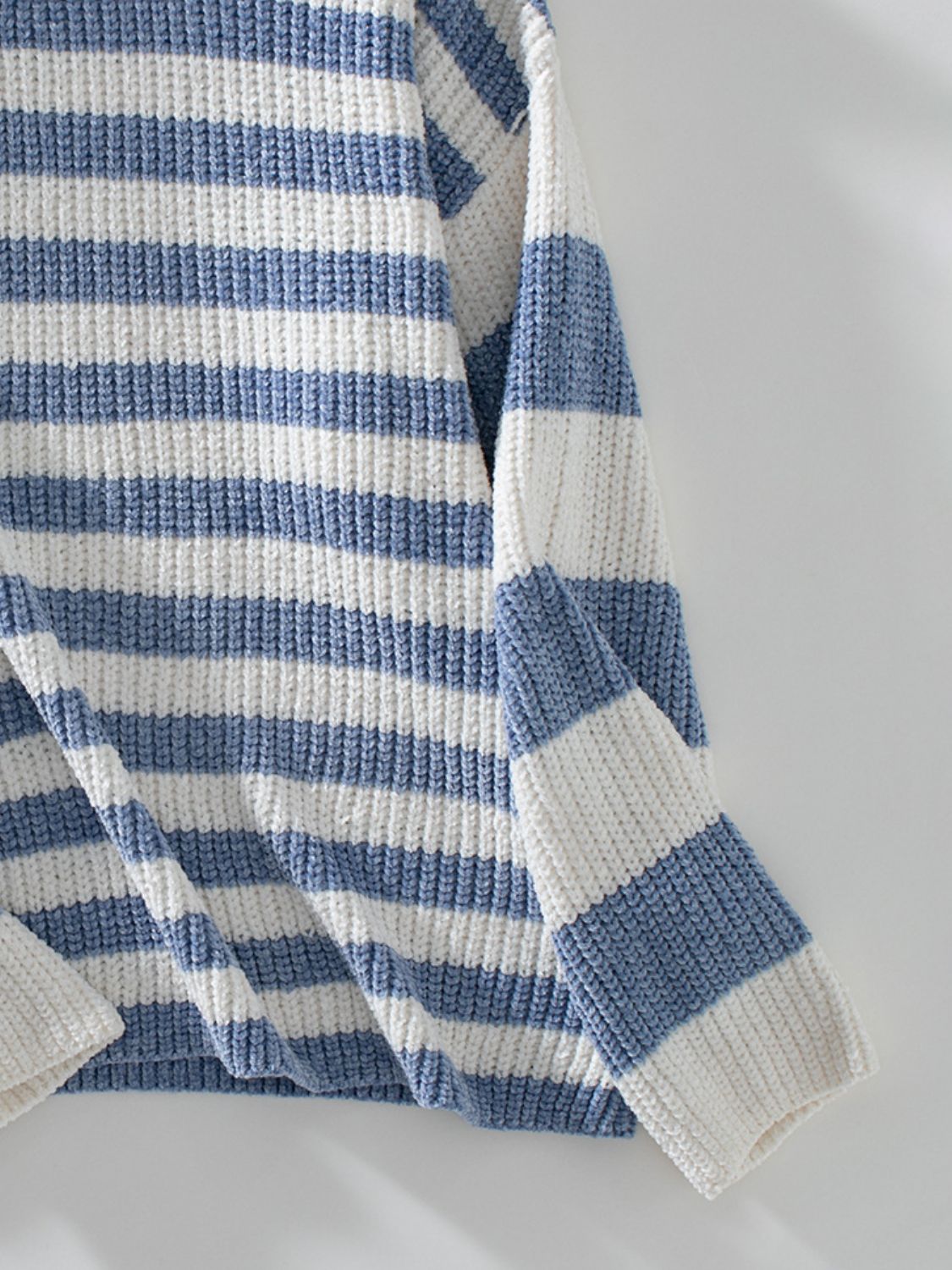 Light blue and white striped crewneck sweater with a ribbed knit texture.