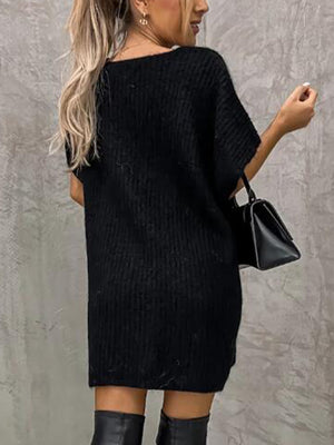Black knit tunic with short sleeves and a relaxed fit, styled with a handbag.