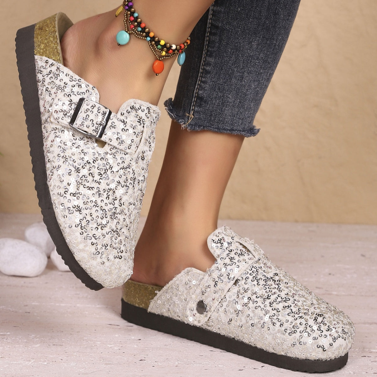 White sequin slip-on mules with decorative buckle detail.