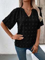 Black Swiss dot blouse with short sleeves and a V-neckline.