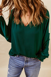 Green voluminous sleeve blouse with ruched cuffs and V-neck.