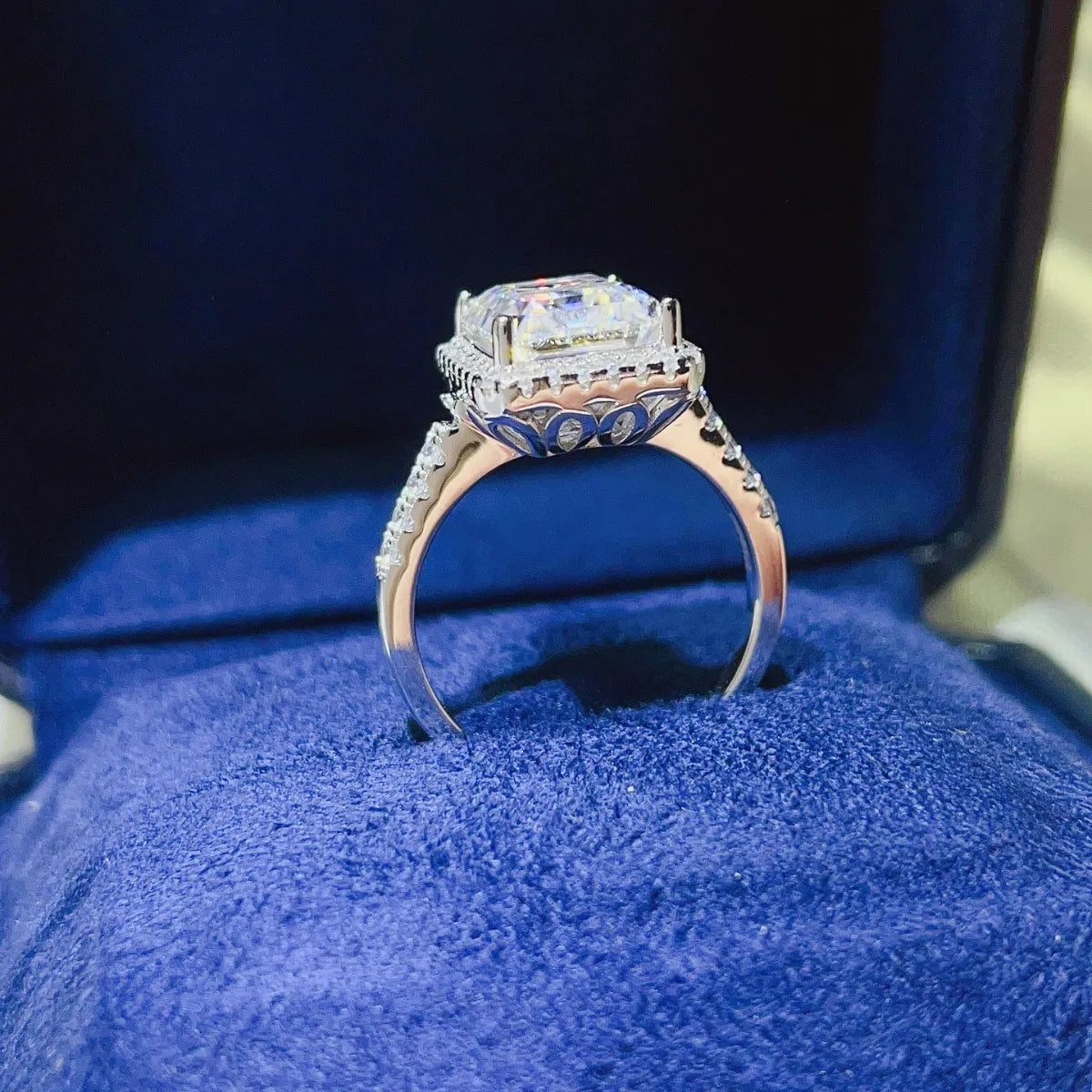 Emerald cut moissanite halo ring in sterling silver with pavé band details.