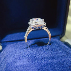 Emerald cut moissanite halo ring in sterling silver with pavé band details.