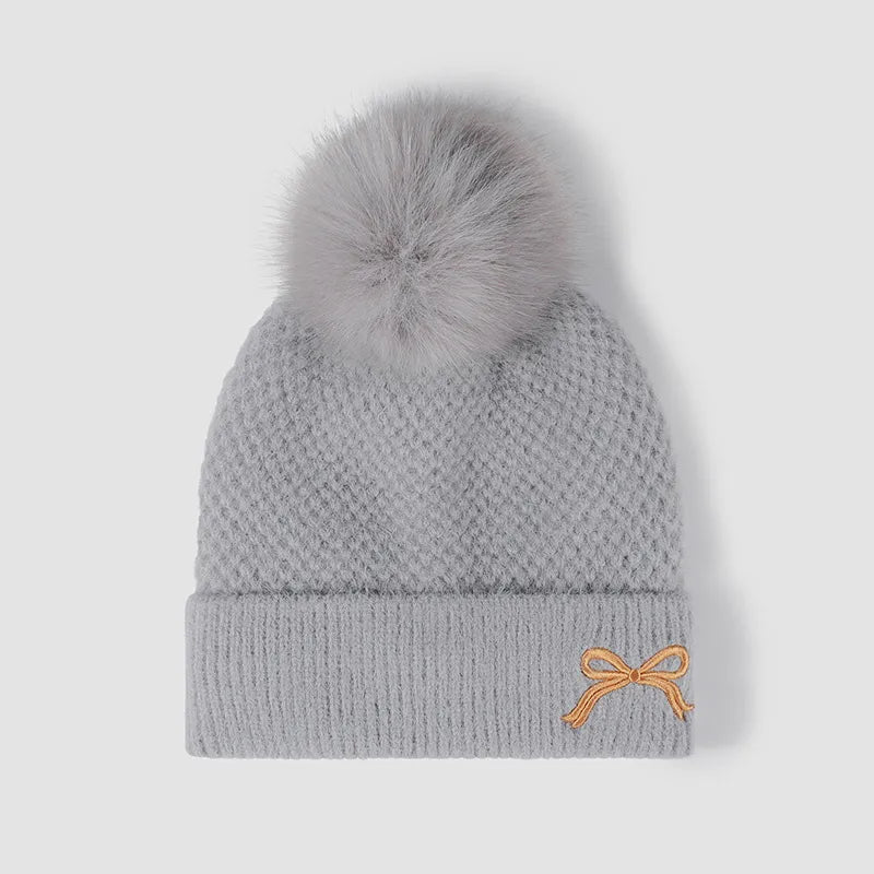 Gray knit beanie with pom-pom and embroidered bow detail
