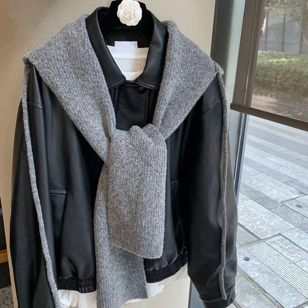 Gray hooded knit tie scarf draped over a black jacket.