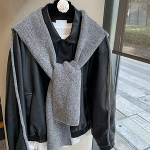 Gray hooded knit tie scarf draped over a black jacket.