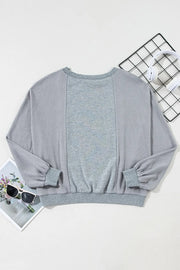 Gray waffle knit top with contrasting gray panels and balloon sleeves.