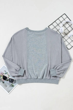 Gray waffle knit top with contrasting gray panels and balloon sleeves.