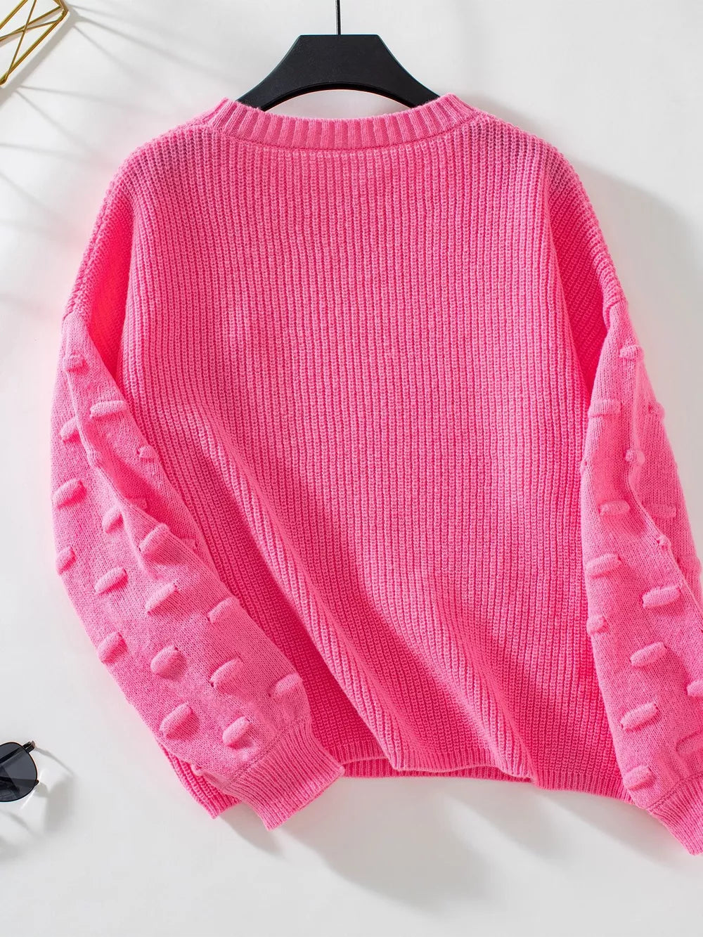 Hot pink knit sweater with textured bobble sleeves and crew neck.
