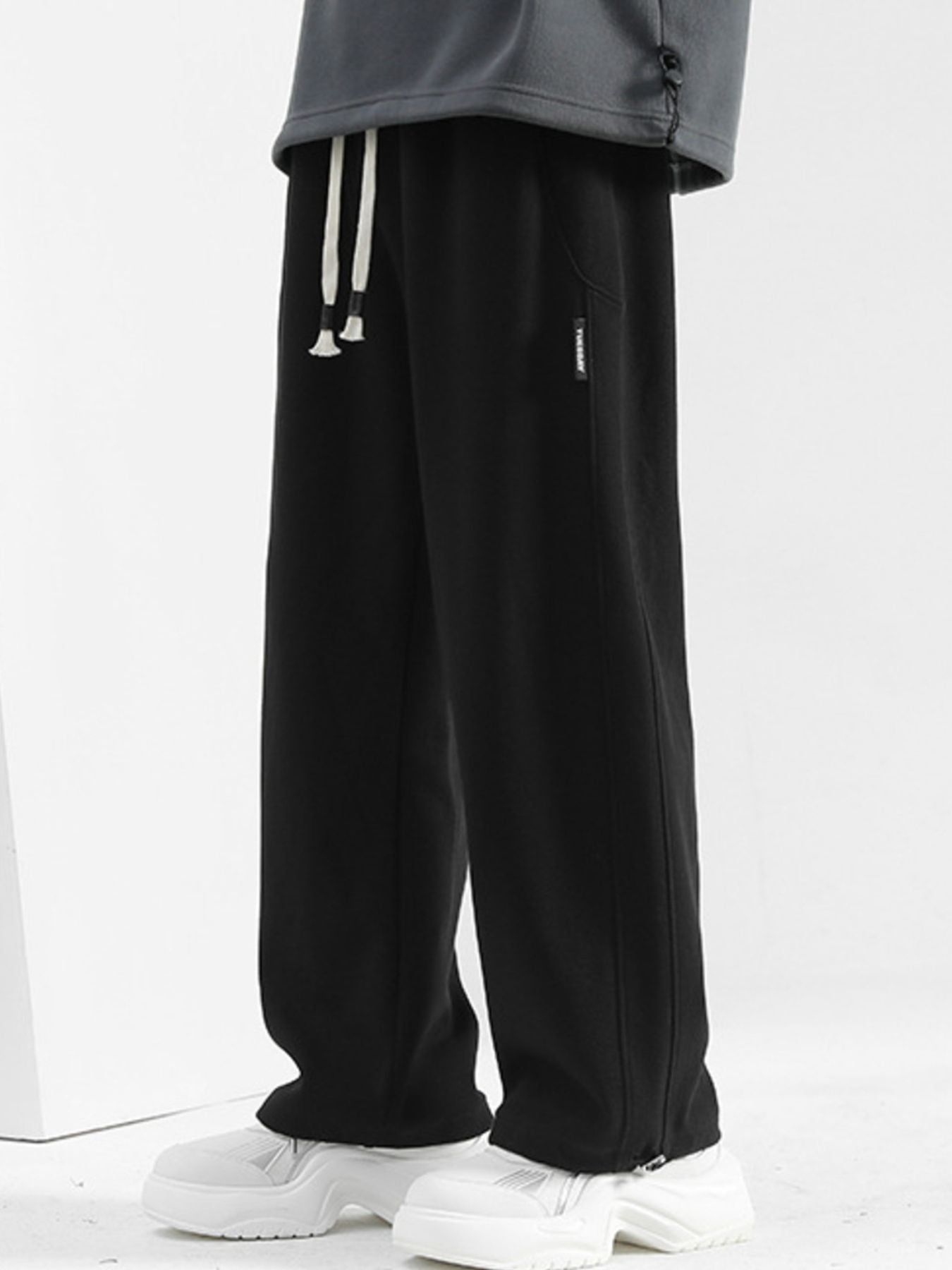 Men's black casual drawstring sweatpants with a loose fit and side pocket detail.