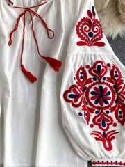White peasant blouse with red and blue embroidery, tie neck with tassels.