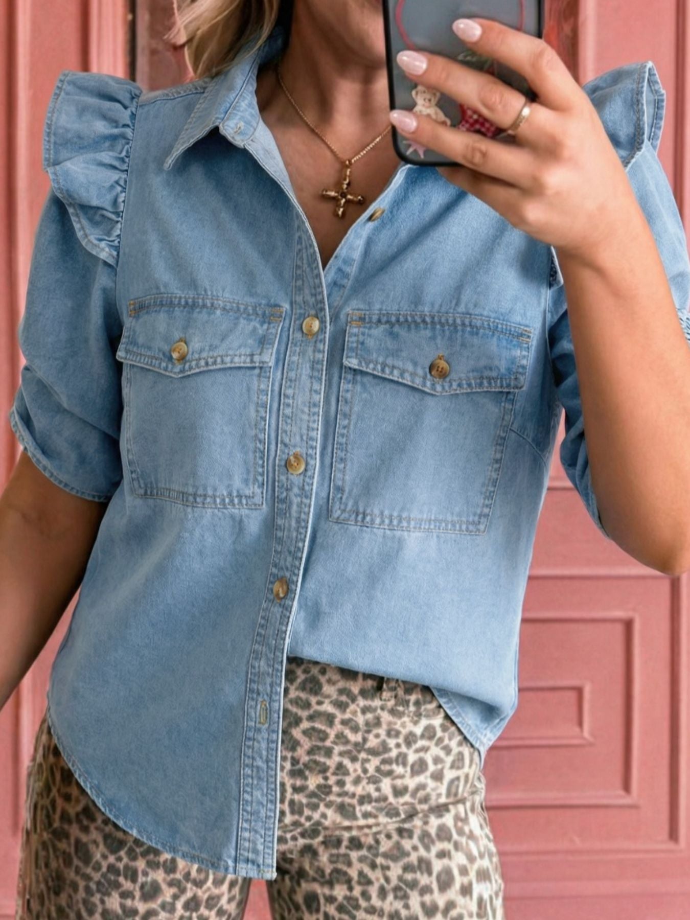 Light wash denim button-down shirt with ruffled short sleeves and chest pockets.