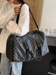Chic checkered travel bag with black leather accents and shoulder strap.