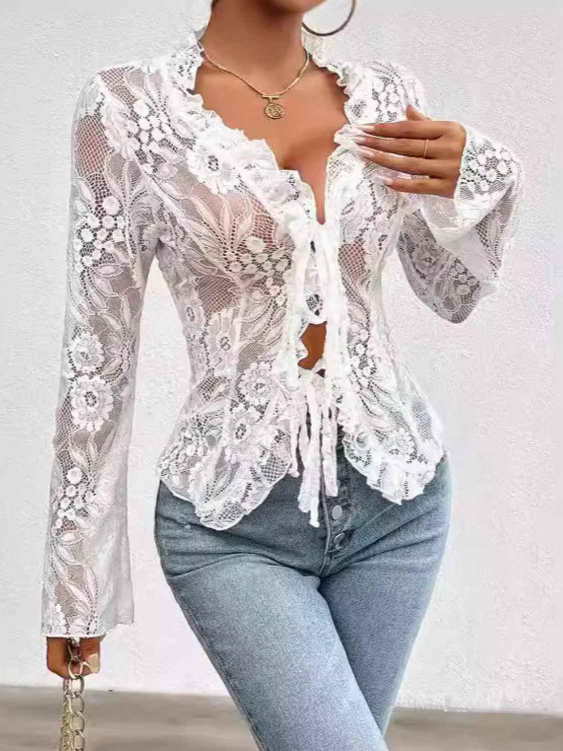 White lace tie-front blouse with floral pattern and ruffled neckline.