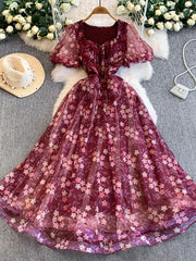 Crimson floral maxi dress with sweetheart neckline, puff sleeves, and sheer overlay.