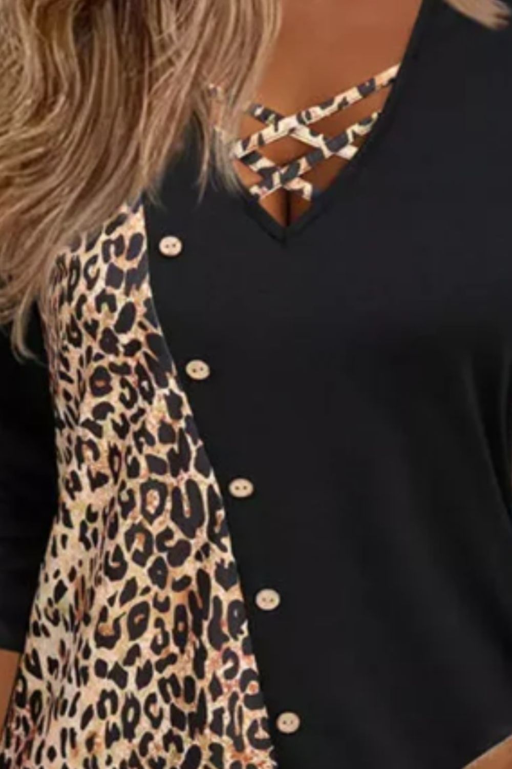 Black blouse with leopard print panel, crisscross neckline, and button detail.