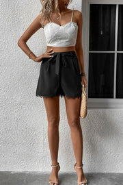 Black high-waisted shorts with tie-waist and lace hem detail.