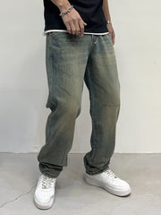 Men's loose-fit jeans in blue-green wash with distressed details and a relaxed cut.