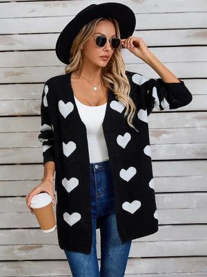 Black acrylic cardigan with white heart intarsia pattern, open front, long sleeves.