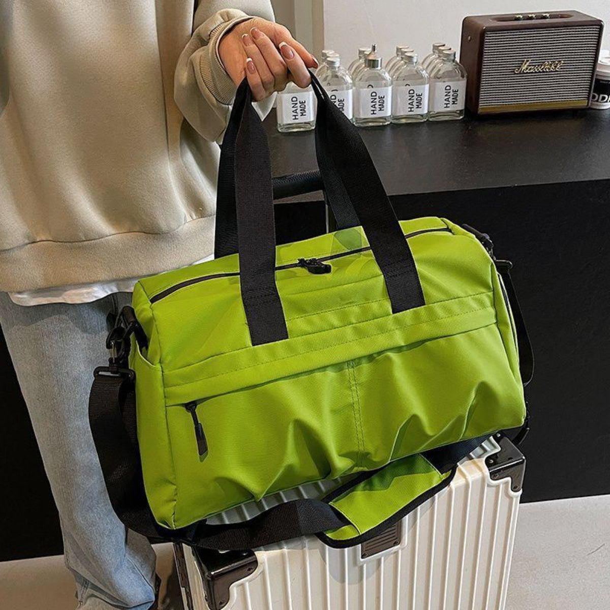 Green nylon travel duffel bag with black straps and multiple zippered pockets.