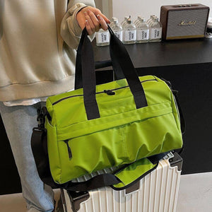 Green nylon travel duffel bag with black straps and multiple zippered pockets.