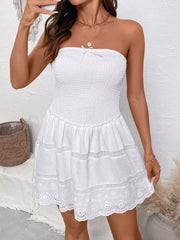 White smocked strapless mini dress with eyelet hem and bow detail.