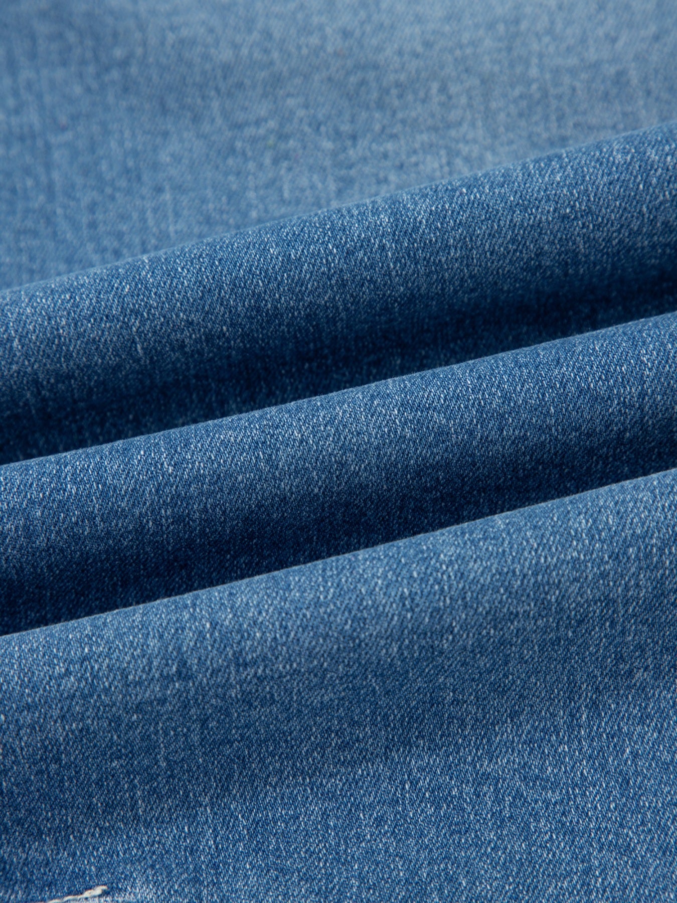 Blue denim fabric detail of high-waisted cuffed barrel jeans