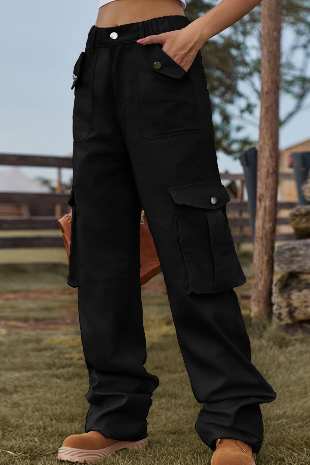 Black utility cargo pants with wide legs and multiple snap-button pockets.