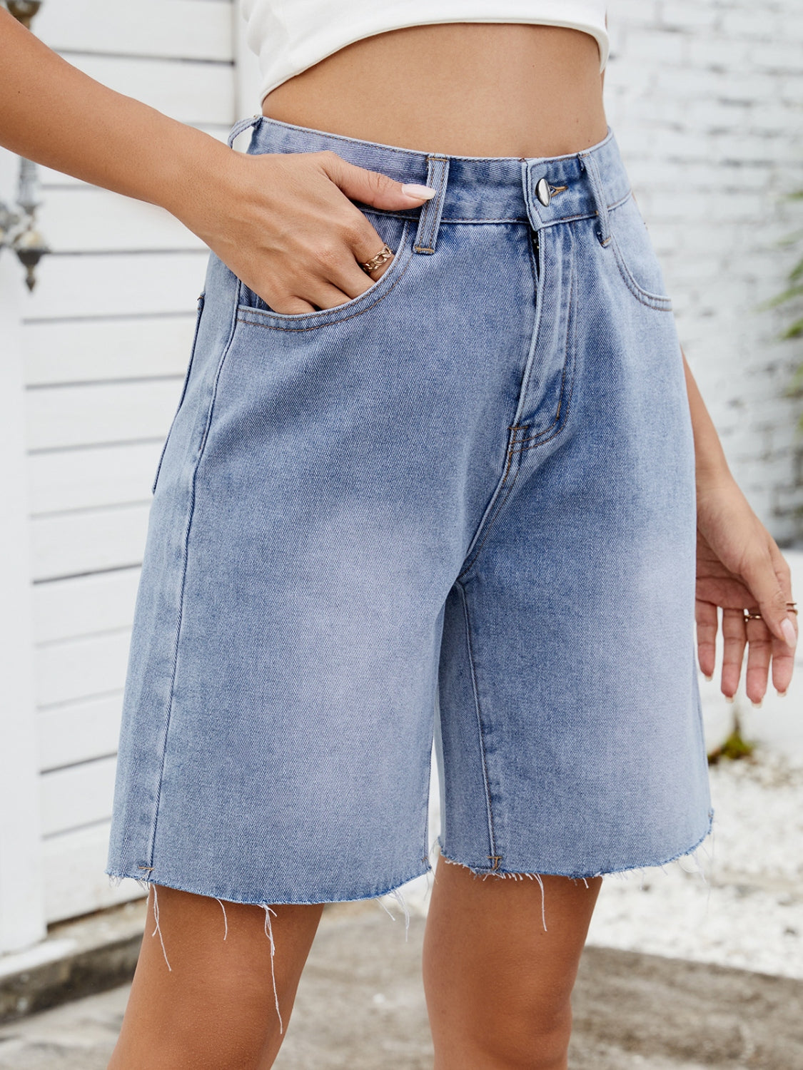 Longline denim shorts in medium wash with a raw hem and relaxed fit.