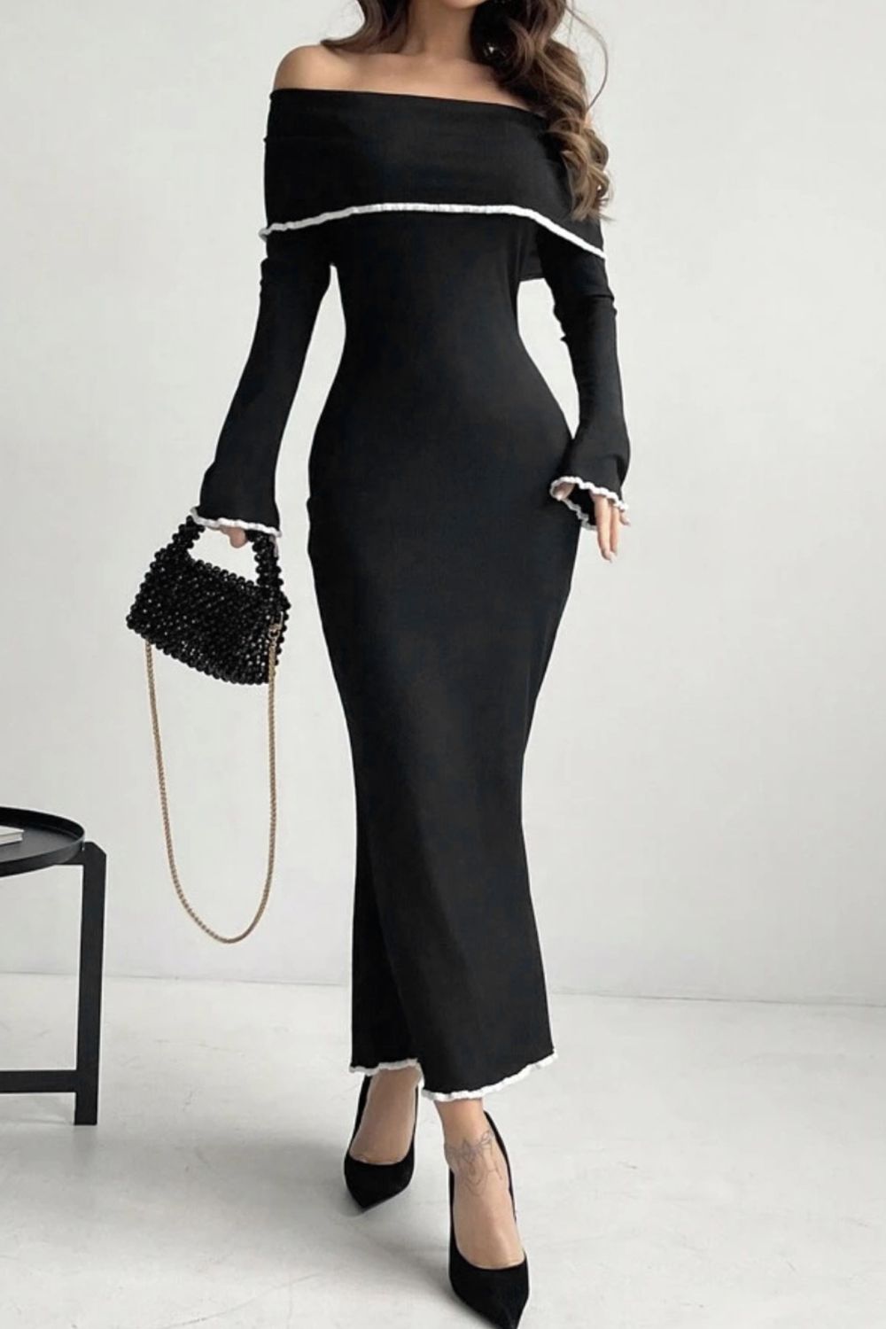 Black off-shoulder maxi dress with ruffled trim and long sleeves.