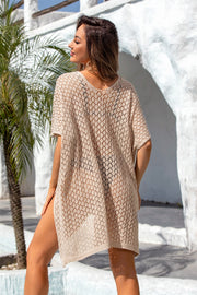 Open-knit beach poncho in Sand with short sleeves and a V-neck, styled casually over swimwear.