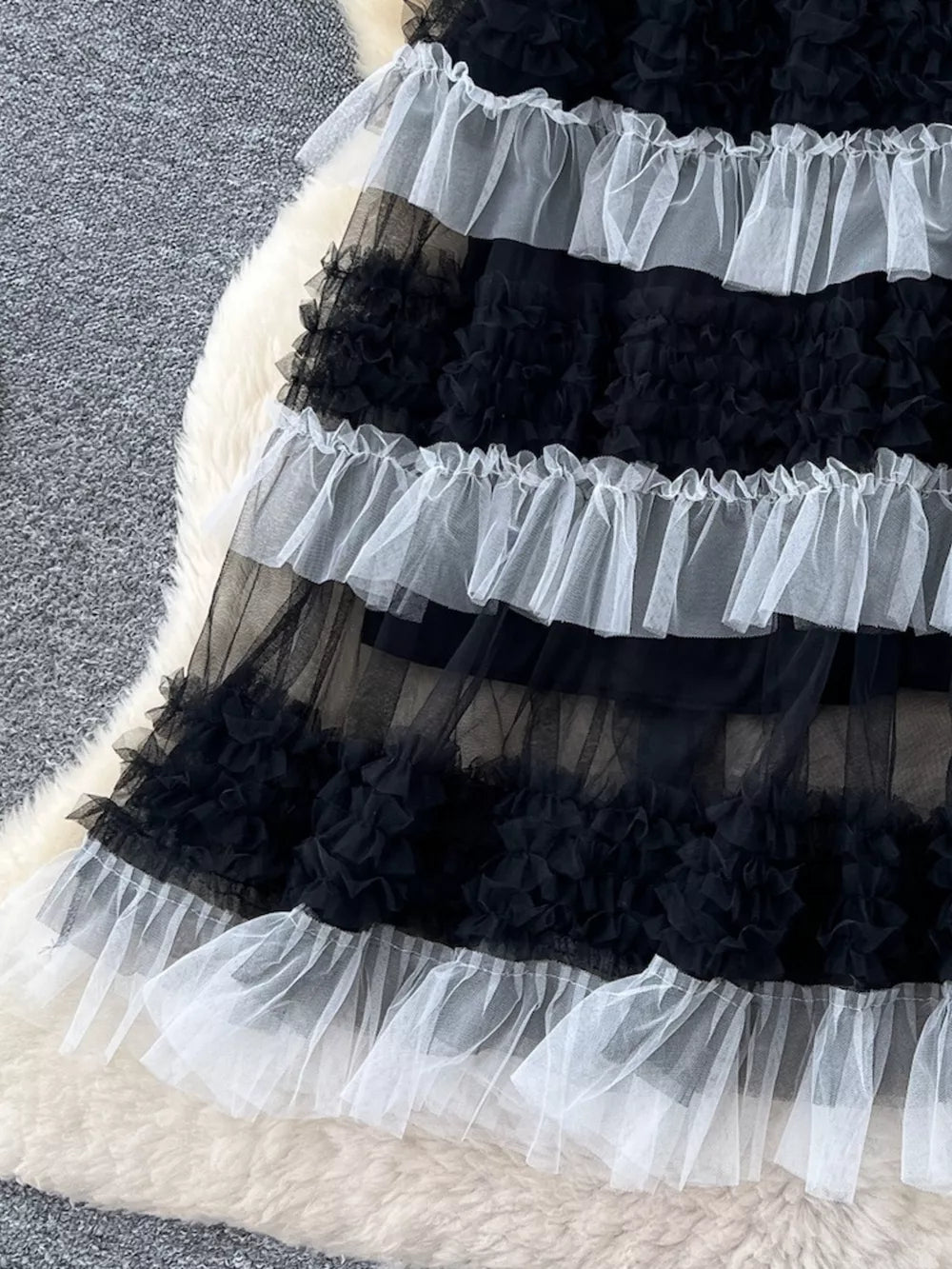 Black and white tiered tulle skirt with ruffle details and a sheer overlay.