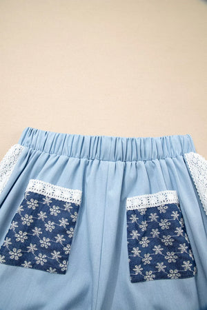 Light blue maternity pants with elastic waist, lace trim, and snowflake-patterned pockets.