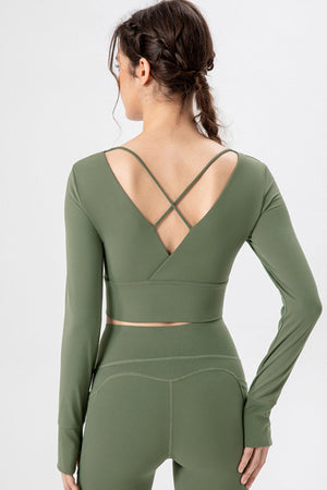 Matcha green crop top with long sleeves, thumbholes, and crisscross back straps.