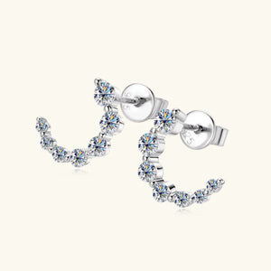 Silver celestial arc moissanite stud earrings with sparkling stones.