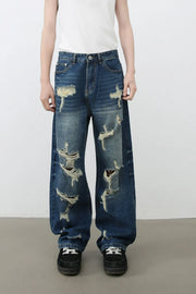 Oversized ripped denim jeans in medium wash with wide-leg silhouette and distressed details.