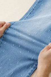 Light wash denim jeans with distressed details and a raw hem.