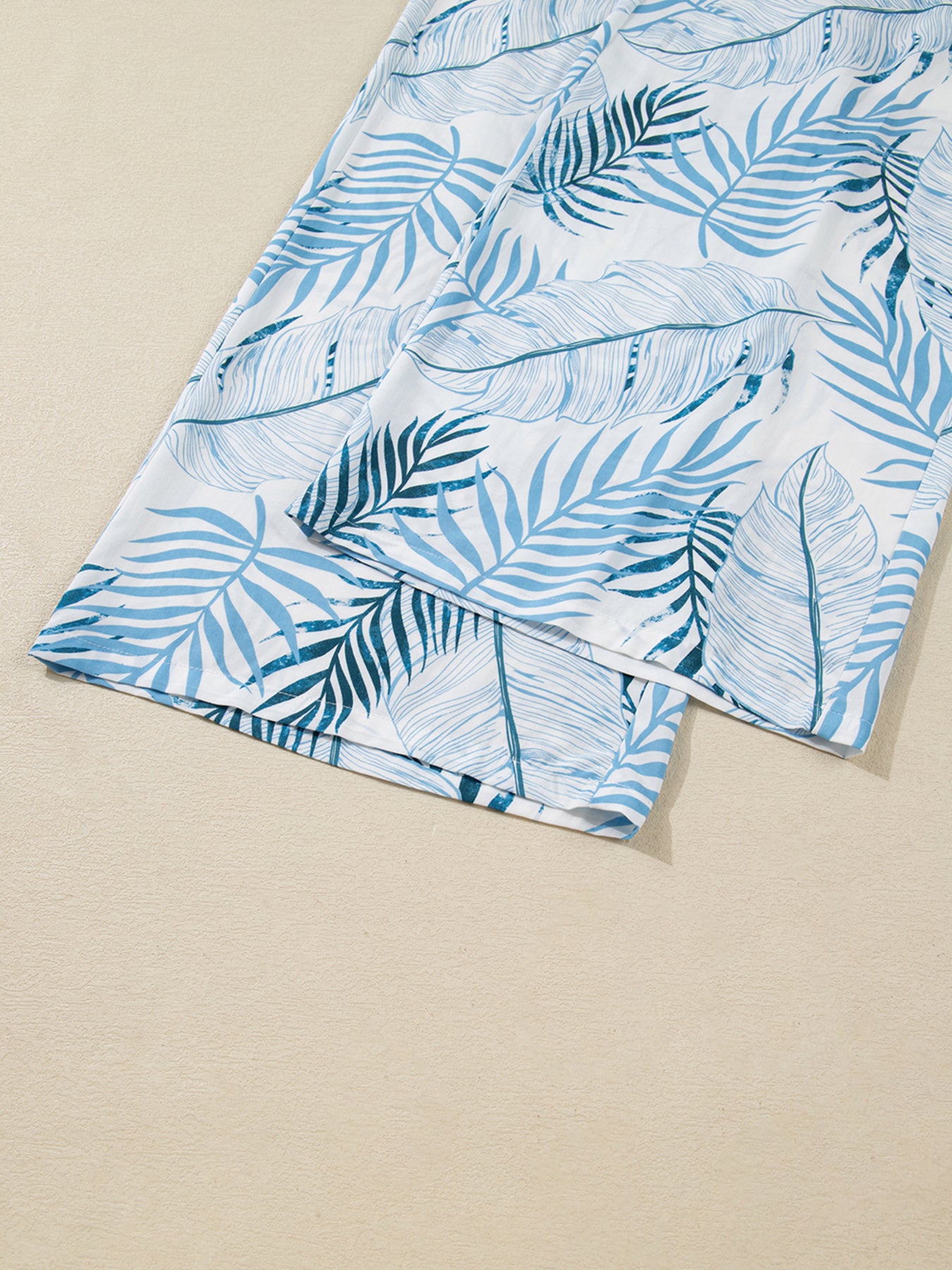 Tropical leaf print wide leg pants in white with blue foliage pattern, cotton.