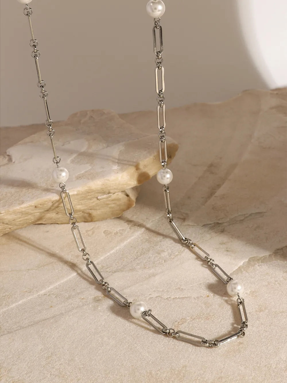 Silver two-tone pearl link necklace with elongated oval chain links and small white pearls.