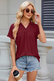 Burgundy gathered yoke polo top with short sleeves and a V-neck collar.