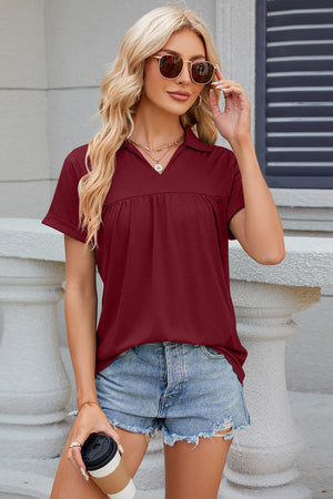Burgundy gathered yoke polo top with short sleeves and a V-neck collar.