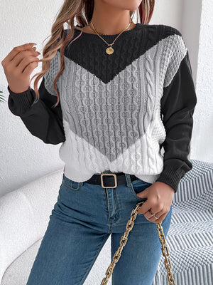 Chevron cable knit sweater with contrast black, gray, and white panels.