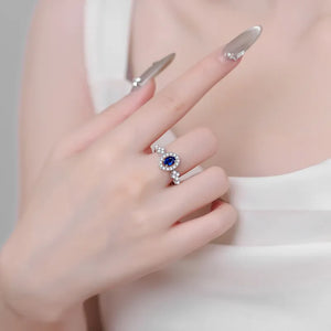 Silver sapphire halo and diamond cluster ring on a hand